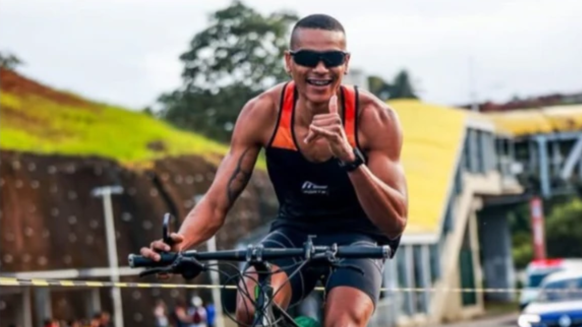 atleta numa bicicleta fazendo saudação para a câmera