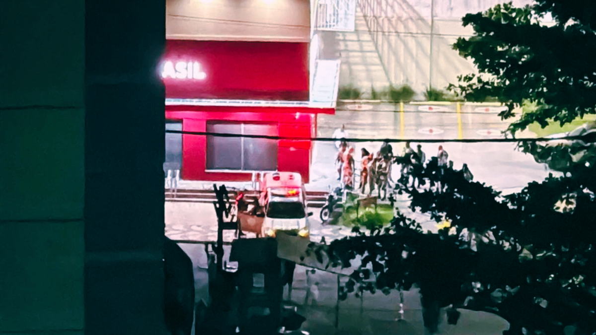 fachada de farmácia com viatura policial e pessoas na frente