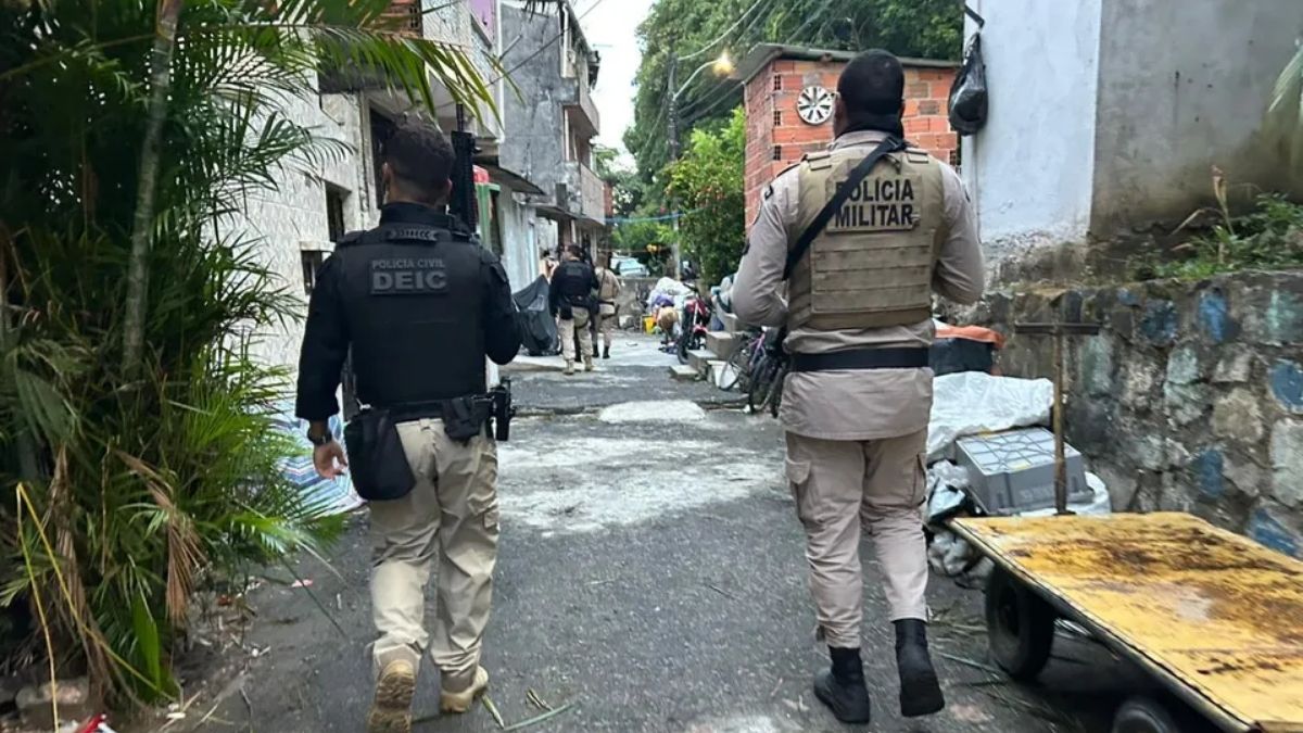 um policial civil e um militar andando lado a lado numa comunidade.